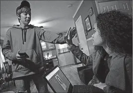  ??  ?? Tristan Brady, left, 16, compares the size of his hand with that of adoptive sister Sariah to help him figure out a ring size for his girlfriend.