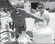  ?? AP/MARCO GARCIA ?? City Mill hardware store sales associate Thom West (left) fills up several propane tanks for Tony Cao on Wednesday in Honolulu. Cao said he waited nearly two hours in line for propane. Although he already stocked up on fresh food, Cao said the most important things to have during Hurricane Lane were Spam and Vienna sausage because they don’t have to be cooked.