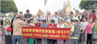  ?? SEKSAN ROJJANAMET­AKUN ?? Chinese tourists take a picture at the Grand Palace. Visitors from China will be exempt from visa-on-arrival fees in November and December.