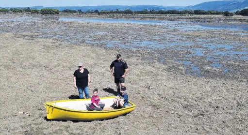  ?? PHOTO: STEPHEN JAQUIERY ?? Browned off . . . Dairy farm manager Dale Harris (right) and family members (from left) Jaclyn, Lexi (6) and Lane (8) try to make light of the situation, after their lush summer pastures were killed by flooding last week.