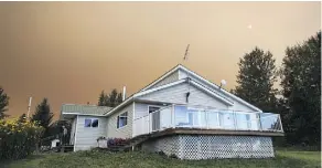  ??  ?? Monica Walther walks down the front steps of her home last week as the Shovel Lake wildfire burns in the distance.