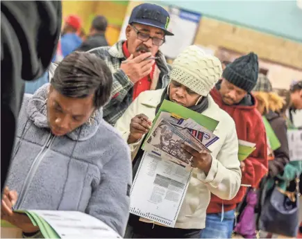  ?? KIMBERLY P. MITCHELL/USA TODAY NETWORK ?? Lela Jamison, 53, center, of Detroit looks over her ballot as she waits to vote at Bow Elementary School, which hosted multiple precincts in the city Tuesday.