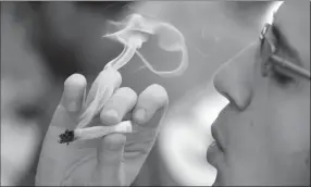  ?? Canadian Press photo ?? A man smokes a marijuana joint at a party celebratin­g weed in Seattle in 2016. Health providers are warning Canadian parents and other adults about the potential dangers to children of exposure through second-hand smoke or the ingestion of cannabis-laced edibles.