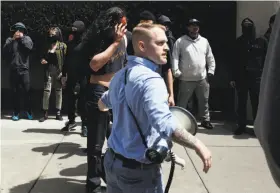  ?? Leah Millis / The Chronicle ?? BERKELEY, APRIL 15: A man with a gashed head walks behind Nathan Damigo, founder of the white supremacis­t group Identity Evropa, as a rally turned violent.