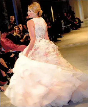  ??  ?? A fairy-tale Lazaro wedding gown from She Said Yes Bridal features a floral print, tiered petticoats and a sheer overlay.