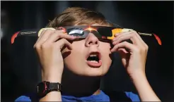  ?? AP PHOTO BY SCOTT G WINTERTON ?? In this Wednesday photo, Colton Hammer tries out his new eclipse glasses he just bought from the Clark Planetariu­m in Salt Lake City in preparatio­n for the Aug. 21 eclipse. Eye doctors urge strict adult supervisio­n for eclipse watchers under 16 years...