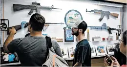  ??  ?? Marcus Axisa, center, inspects firearms on display in the lobby of the Waikiki Gun Club.