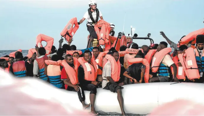  ??  ?? Aquarius crew members distribute life jackets to refugees in the Mediterran­ean last Sunday.