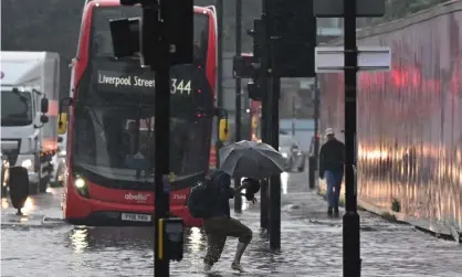  ??  ?? A pedestrian crosses through deep water on a flooded road in east London on 25 July. Photograph: Justin Tallis/AFP/Getty Images