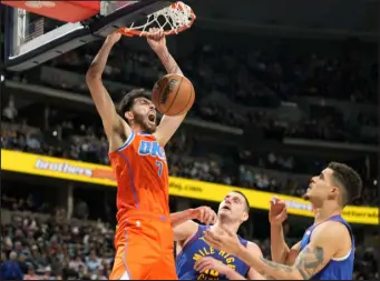  ?? DAVID ZALUBOWSKI — THE ASSOCIATED PRESS ?? Oklahoma City Thunder forward Chet Holmgren, left, reacts after dunking over Nuggets center Nikola Jokic, center, and forward Michael Porter Jr. in the second half of Saturday’s game at Ball Arena.