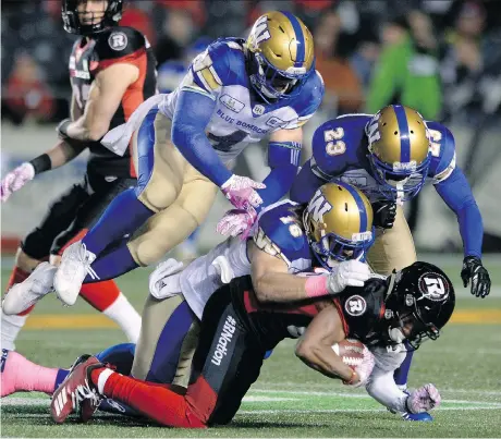  ?? THE CANADIAN PRESS ?? Blue Bombers tacklers Adam Bighill, Taylor Loffler and defensive back Anthony Gaitor pile on Redblacks wide receiver Diontae Spencer during first half action on Friday night in Ottawa. The Bombers defence kept Ottawa’s attack in check for most of the night in a 40-32 OT victory.