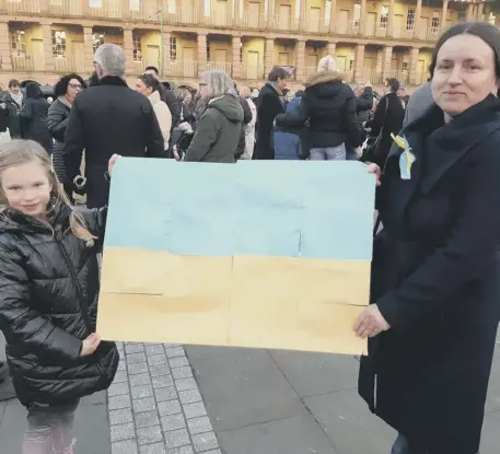  ?? ?? SUPPORT: Tetyana Lyuta and her daughter with their Ukrainian flag (main photo) at the emotional vigil at The Piece Hall on Saturday. Above: Ukrainian soldiers in besieged Kyiv