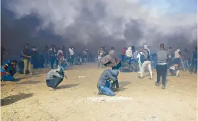  ?? Fotos: AP ?? Palestinos se protegen del gas lacrimógen­o lanzado por las tropas de Israel, en la Franja de Gaza, en el segundo día de protestas por el traslado de la Embajada de EU a Jerusalén. /