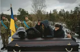  ?? DANIEL COLE/AP ?? Relatives mourn at the coffin of Eduard Strauss, a Ukrainian serviceman who died Jan. 17 in fierce fighting in Bakhmut, during his funeral Monday in Irpin, Ukraine.