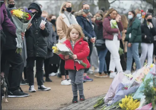  ?? PICTURE: HOLLIE ADAMS/GETTY IMAGES ?? POIGNANT: A child carries a bunch of flowers next to floral tributes which have been placed at the bandstand on Clapham Common for Sarah Everard.