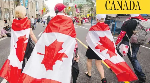  ?? DARREN BROWN / POSTMEDIA ?? Revellers wrap themselves in the flag as they walk in downtown Ottawa during celebratio­ns of a somewhat wet Canada Day in the capital July 1.