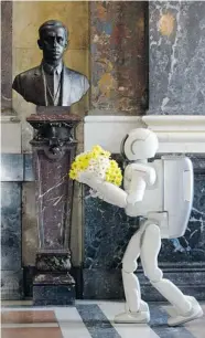  ?? DAN MATERNA/AFP/Getty Images ?? Walking robot Asimo, a 1.2-meter tall robot made by Honda, lays a bunch of flowers at the bust of Czech writer Karel
Capek at the Czech National Museum in Prague.