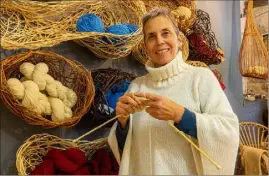  ??  ?? Isabelle, aiguilles et laine maralpine en mains, présente un exemple de poncho créé à l’atelier de Laine rebelle, marque Valléroise. (Photo Jackie Dieren)
