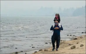  ?? The Associated Press ?? Presley Mila Perez gets a ride on the shoulders of George Estrada as they walk along the shores of Lake Tahoe, Calif., Tuesday.