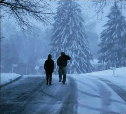  ?? ASSOCIATED PRESS ?? A family walks down a snowy Marple street during last Friday’s winter storm.