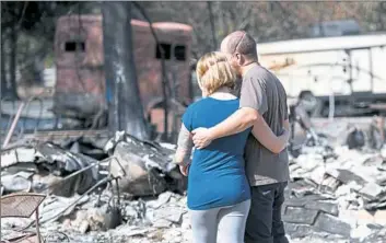  ?? Josh Edelson/AFP/Getty Images ?? Mandi and Lane Summit embrace before their fire-destroyed home on Sunday in Redwood Valley, Calif.