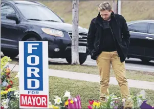  ?? CP PHOTO ?? Michael Ford, the nephew of the late Rob Ford, looks at the flowers left earlier this year at Douglas B. Ford Park in Etobicoke.
