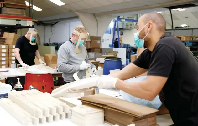  ?? Reuters ?? ↑
Employees at a company making disposable visors in Cuffley, UK.