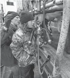  ?? MARK HOFFMAN/MILWAUKEE JOURNAL SENTINEL ?? Kendra Thewis is aided by her 7-year-old daughter, Starr, with the chores in the milking parlor of the family farm near Mellen in rural Ashland County.