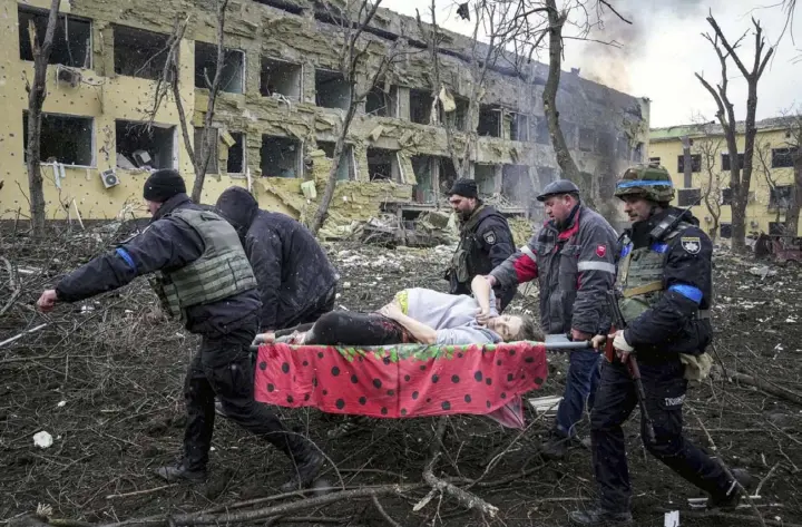  ?? AP Photo/Evgeniy Maloletka ?? Ukrainian emergency employees and volunteers carry an injured pregnant woman from a maternity hospital that was damaged by shelling in Mariupol, Ukraine, March 9, 2022. The woman and her baby died after Russia bombed the maternity hospital where she was meant to give birth.