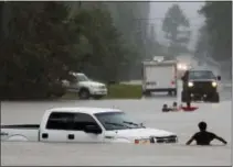  ?? MICHAEL CIAGLO/HOUSTON CHRONICLE VIA AP ?? A man, foreground, checks to make sure everyone made it safely out of a truck that flooded when the three men in the background drove around a closed road barrier along Nichols Sawmill Road and lost control of the vehicle in rising flood water in...