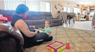  ?? PHOTOS BY AMY BETH BENNETT/SUN SENTINEL ?? Damien Wallace, 21, plays with his daughter, Paisley Wallace, 2, while his aunt, Melanie Toomey, loads the dishwasher Tuesday in Toomey’s Coral Springs home. The Wallace family is from Oak Grove, just outside of Port St. Joe, and their home was badly damaged by Hurricane Michael.