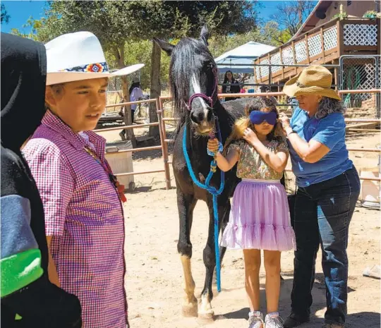  ?? JESSICA PARGA U-T PHOTOS ?? Heart-N-Soul founder Jaye Strother fits Melody Andraca with a blindfold before she leads a horse through an obstacle course as part of a trust exercise.