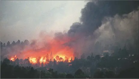  ?? SANTA FE NEW MEXICAN FILE PHOTO ?? The Cerro Grande Fire burns homes on Los Alamos’ west side in 2000. About 400 people were displaced by the fire. The fire prompted residents to allow more thinning and prescribed burning work within the town and convinced property owners to maintain defensible space around their houses in case of wildfire.