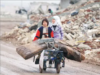  ?? KHALIL ASHAWI / REUTERS ?? Samah, 11, and her brother, Ibrahim, transport their salvaged belongings from their damaged house in Aleppo, Syria, on Monday.