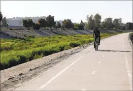  ??  ?? A BICYCLIST rides along Compton Creek just north of Del Amo Boulevard, where the body of Kenneth Jones was found. He had been beaten and stabbed.