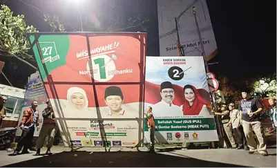  ?? GALIHCOKRO/JAWA POS ?? AKHIRI KAMPANYE: Petugas KPU merobohkan dua baliho pasangan calon kepala daerah Jatim di Jalan Indrapura, Surabaya, kemarin dini hari.