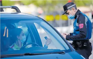  ?? /AFP ?? Un agente de la policía comprueba la identifica­ción de un conductor en un puesto de control de tráfico, para controlar el movimiento de personas en Madrid