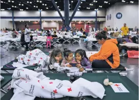  ?? JABIN BOTSFORD/THE WASHINGTON POST ?? From left, Angelina De Los Santos, 7, Vanessa Pasillas, 2 and Jade De Los Santos, 5, watch videos Monday with Rosemarie Pasillas. They were among the thousands who sought shelter at a convention center in Houston.