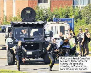  ??  ?? Police and Royal Canadian Mounted Police officers survey the area of a shooting in Fredericto­n, New Brunswick, Canada