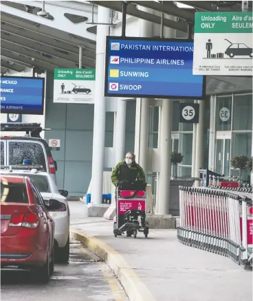  ?? PETER J. THOMPSON / NATIONAL POST ?? A traveller wearing a mask walks with luggage outside of Toronto Pearson Airport
on Tuesday during the COVID-19 pandemic.