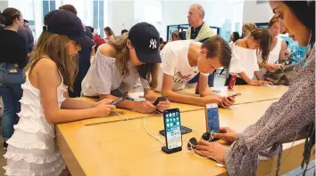  ?? AP file ?? Customers browse in an Apple store in New York. The Commerce Department yesterday issued its July report on consumer spending, which showed a sharp surge.