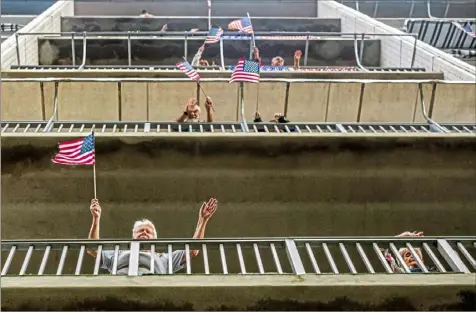  ?? Michael M. Santiago/Post-Gazette ?? Residents wave American flags from their balconies and dance along to music played by Alice Oakes, a retired nurse from Mt. Lebanon, during the “Afternoon Soiree” on Friday at Bower Hill apartments in Mt. Lebanon.