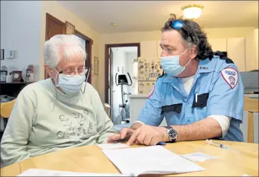  ?? DANIELLE RAY / SENTINEL & ENTERPRISE ?? Brewster Ambulance Service EMT Rob Barss reviews some questions with Abigail Letourneau prior to giving her the Johnson & Johnson COVID-19 vaccine at her Leominster apartment on Wednesday.