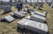  ?? THE ASSOCIATED PRESS ?? Northeast Philadelph­ia Police Det. Timothy McIntyre and another Philadelph­ia police officer look over tombstones that were vandalized in the Jewish Mount Carmel Cemetery on Sunday in Philadelph­ia. A police spokeswoma­n said preliminar­y estimates are...