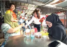  ?? — Bernama photo ?? Pang distribute­s Mother’s Day flowers to a constituen­t during a walkabout at the Kuala Kubu Baharu Market to thank voters for her polls win.