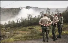  ?? BRIAN VAN DER BRUG/LOS ANGELES TIMES FILE PHOTOGRAPH ?? California Department of Fish and Game wardens take in a view of water from Lake Oroville flowing out of the damaged primary spillway at 100,000 cubic feet per second on Feb. 13, 2017 in Oroville.