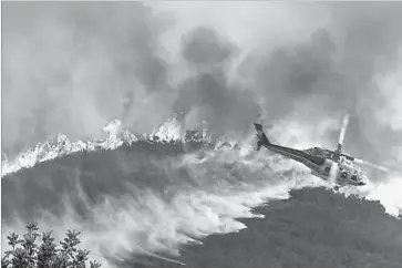  ?? Irfan Khan Los Angeles Times ?? A FIREFIGHTI­NG helicopter drops water on the La Tuna fire in the Verdugo Mountains north of downtown Los Angeles. Approximat­ely 730 homes were placed under evacuation orders in communitie­s around the blaze.