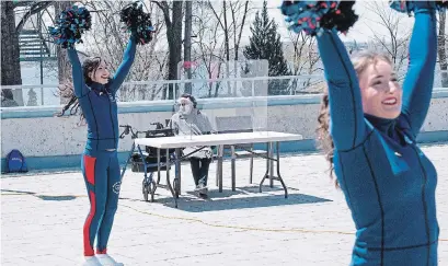  ?? PAUL CHIASSON THE CANADIAN PRESS ?? Pierrette Lalonde-Gosselin, 88, watches as Montreal Alouettes cheerleade­rs perform for seniors on the terrace of the residence Au Fil de l'eau in Montreal on Wednesday. Quebec and Ontario are still seeing hundreds of new COVID-19 cases every day.