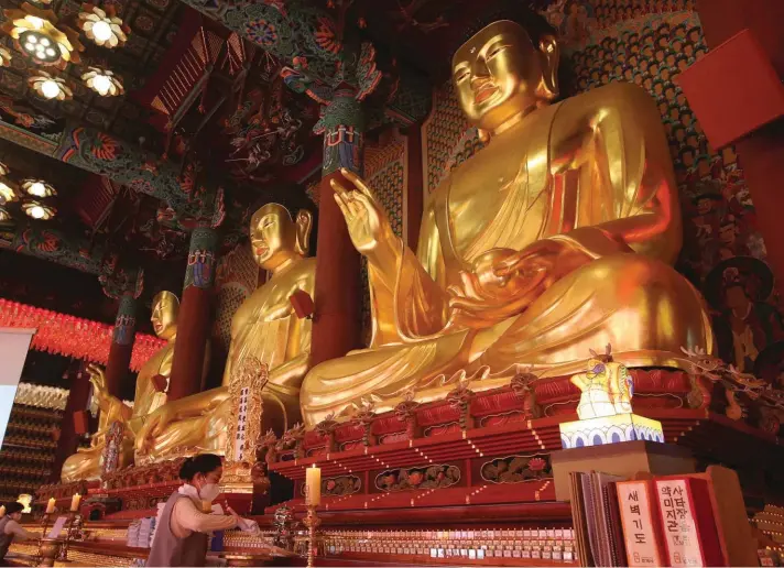  ??  ?? Buddhists wearing face masks as a precaution against the coronaviru­s sweep away dust under Buddha statues during a cleanup yesterday at Jogye Temple in Seoul, South Korea, ahead of Buddha's Birthday, which falls on May 19. Photo: AP