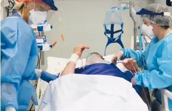  ?? ANTONIO CALANNI/AP ?? Hospital workers tend to a patient Thursday in Pope John XXIII Hospital’s COVID-19 intensive care unit in Bergamo, Italy.